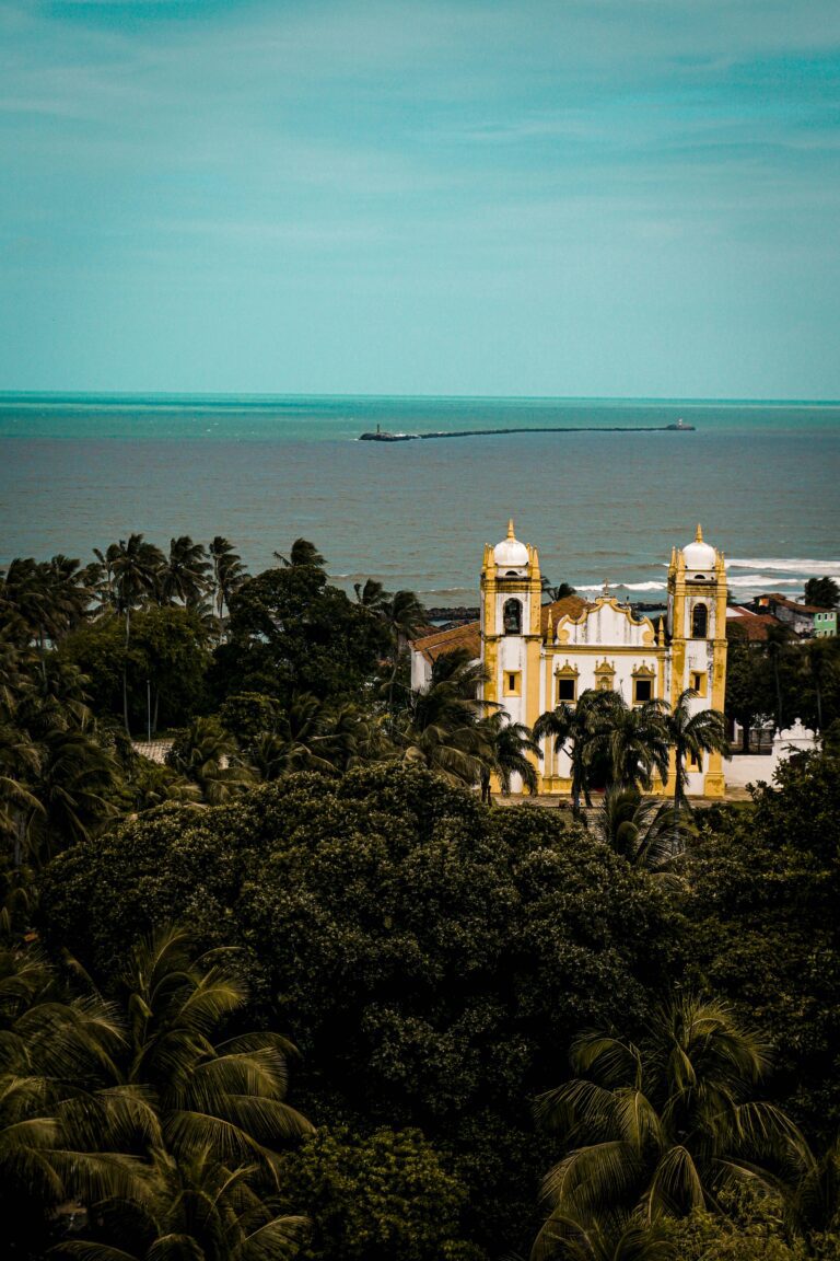 Photo d'Olinda au Brésil : vue de haut sur une église avec la mer et le forêt l'entourant.