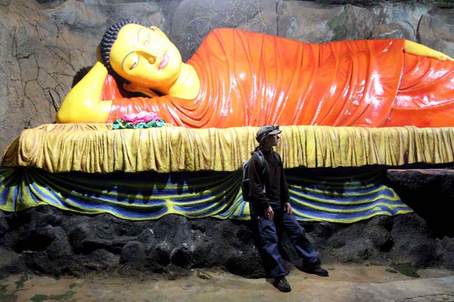 Femme s'appuyant sur le devant d'une statue de bouddha couché.