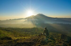 Vue sur le Mont Batur en Indonésie, avec un homme accroupi au premier plan.