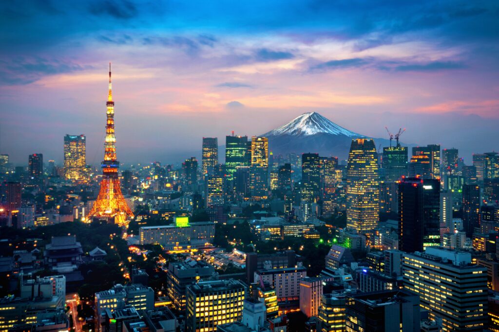 Photo panoramique de Tokyo vu du ciel en début de soirée, avec le Mont Fuji en fond.