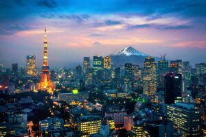 Photo panoramique de Tokyo vu du ciel en début de soirée, avec le Mont Fuji en fond.