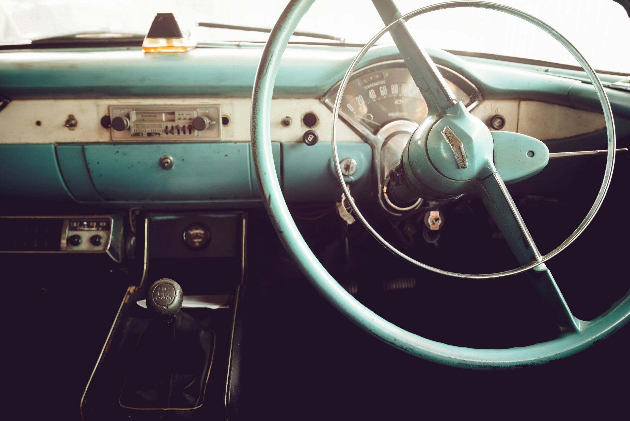 Intérieur d'une voiture vintage bleue clair. Zoom sur le volant et la radio.