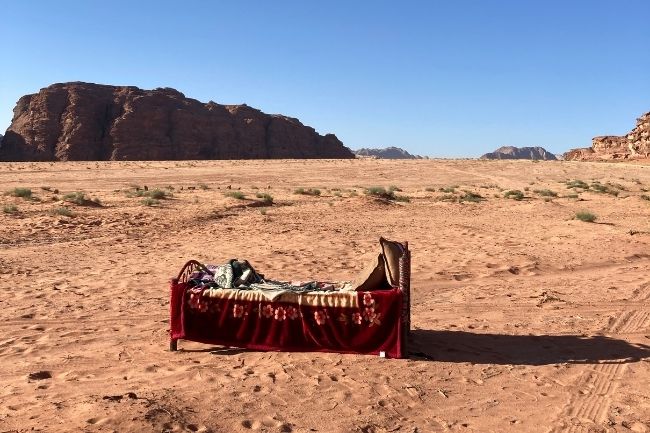 Un lit dans un désert avec des couvertures dessus