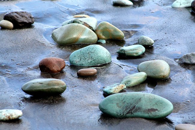 Zoom sur des galets sur une plage de galets bleus.