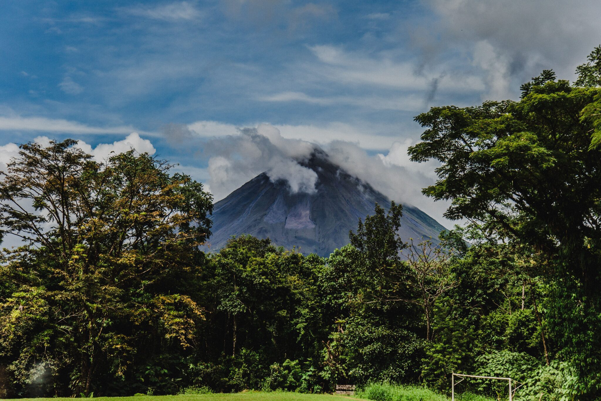 forêt avec un volcan en fond, volcan recouvert de nuage partiellement