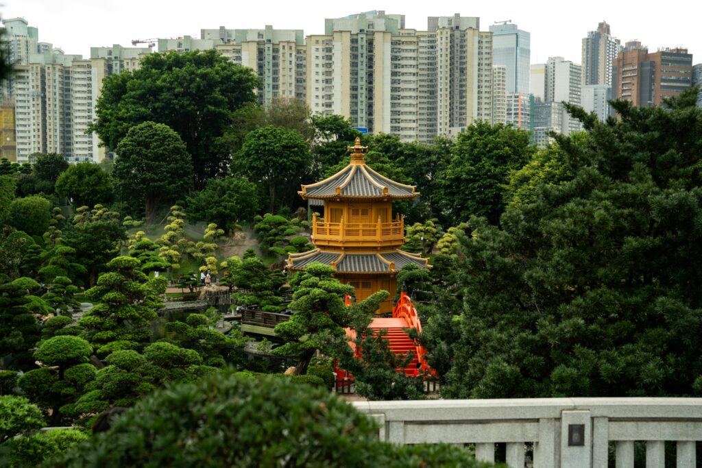 En premier plan : un temple et des arbres. En arrière plan : la silhouette de la ville et ses immeubles.