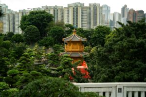 En premier plan : un temple et des arbres. En arrière plan : la silhouette de la ville et ses immeubles.