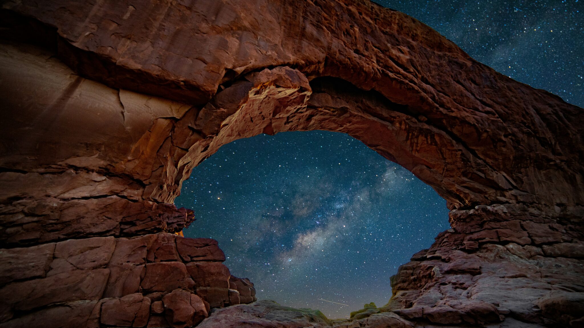 Nuit étoilée en fond avec un arche naturelle créant un recadrage de la photo.