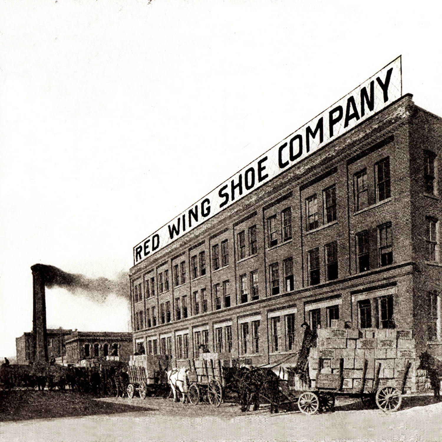 Image de l'usine de 1912 avec le nom de l'entreprise en gros au dessus.