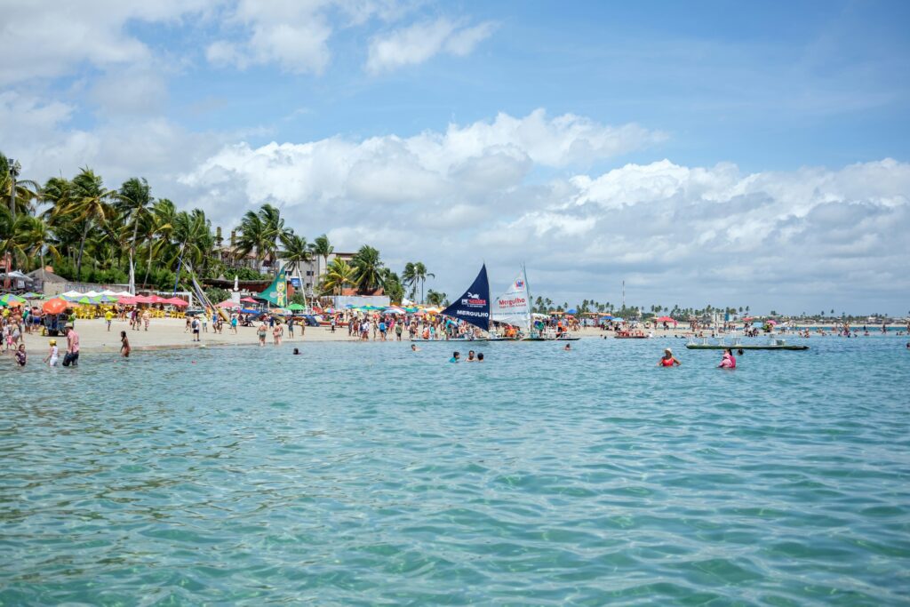mer et plage remplie de personnes et de voiliers à Porto de Galinhas au Brésil.