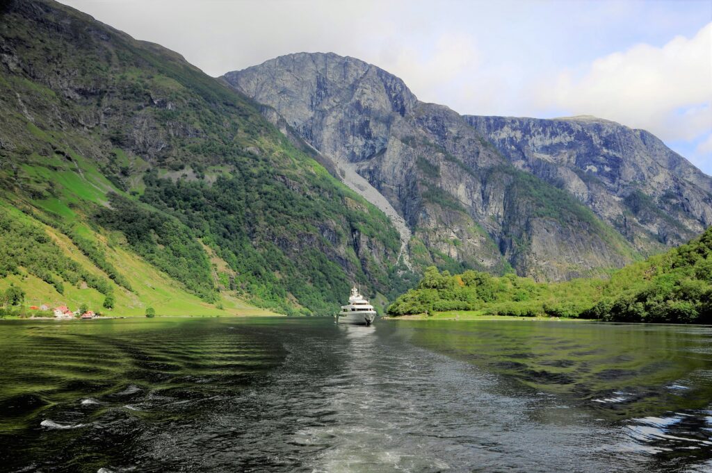 Montagne entourant un lac avec un bateau navigant dessus.