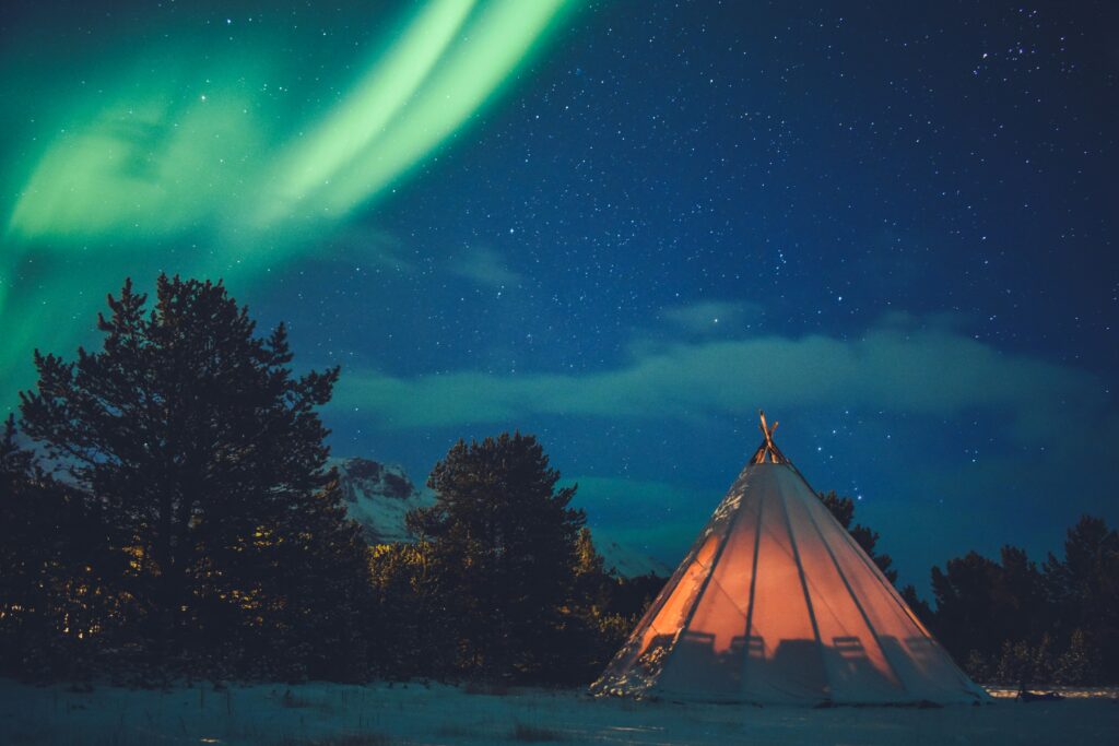Aurore boréale en Norvège avec un tipi en extérieur pour observer le phénomène.