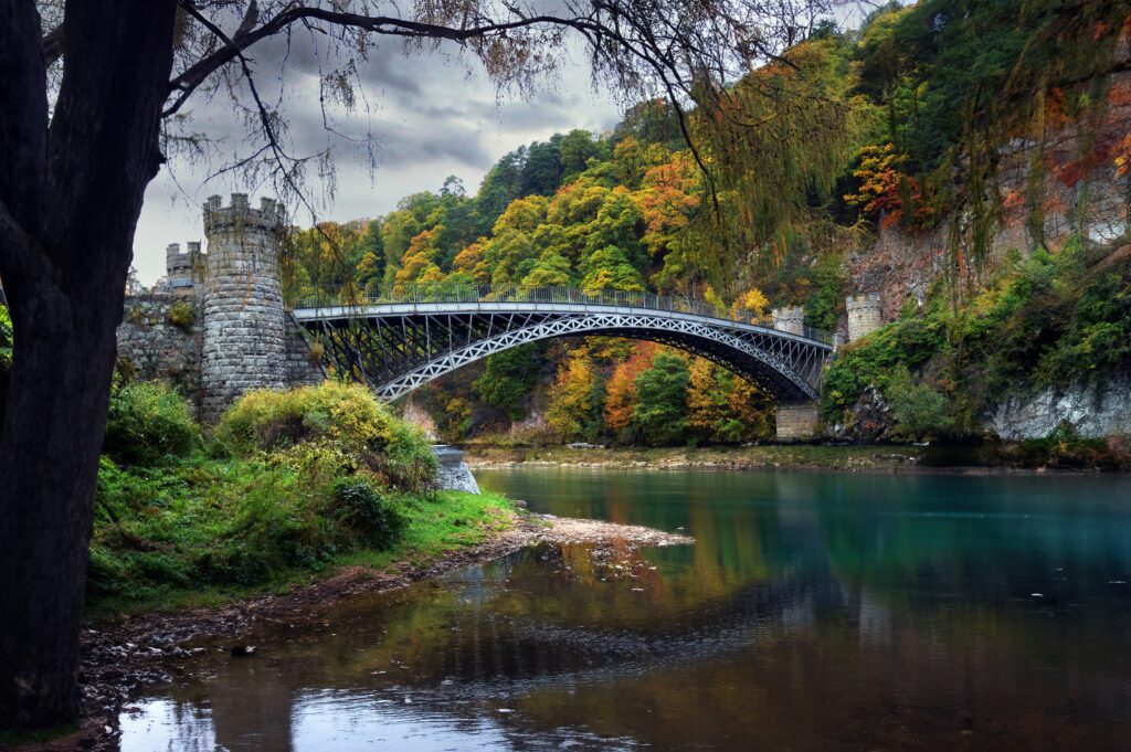 pont en ecosse au dessus d'un ruisseau entouré d'arbres.