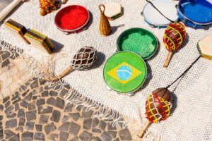 Multiples instruments de musique (samba, forro, bossa nova...), sur un paréo, dont un instrument avec le drapeau brésilien dessus.