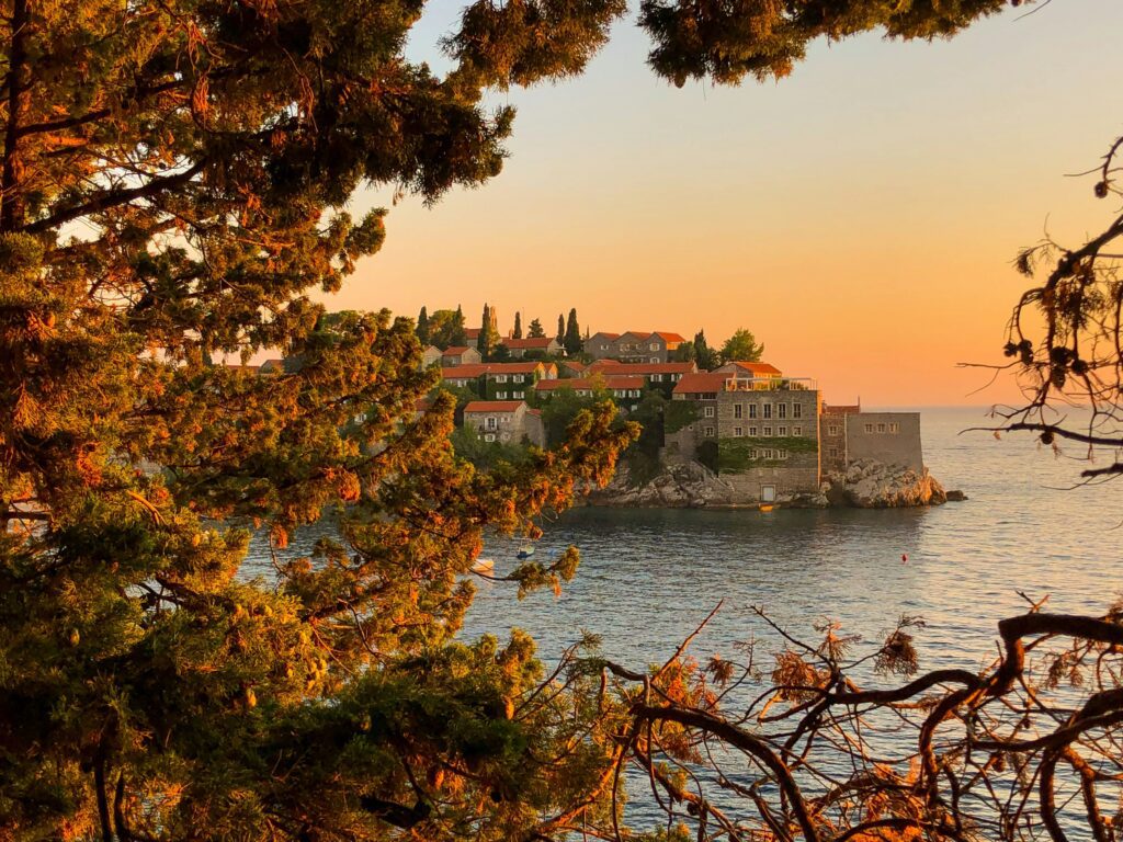Vue a travers des feuilles de sveti stefan au coucher de soleil.