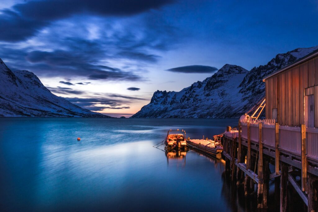 Ponton allant vers un lac en Norvège entouré de montagne et de nuit.
