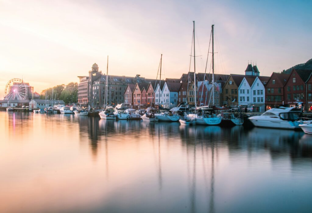 Ville de Bergen en Norvège longeant un lac avec des bateaux à quais devant les maisons.