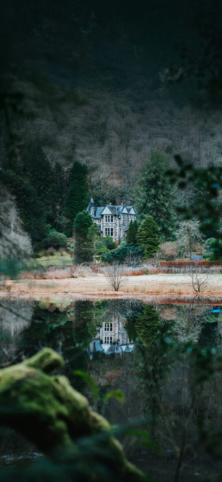 vue d'un lac avec une maison et son reflet sur l'eau au fond.