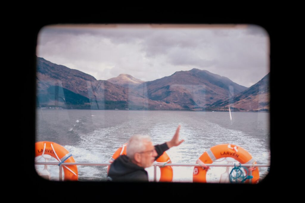 personne sur un bateau saluant avec des montagnes en fond