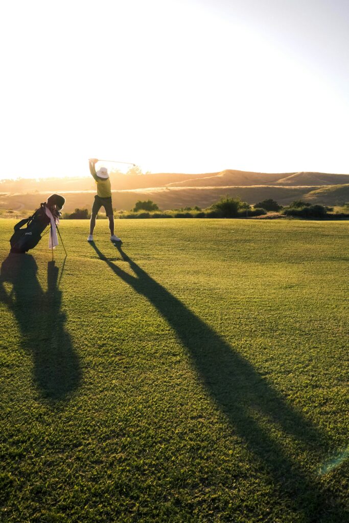 homme golfant au couché de soleil