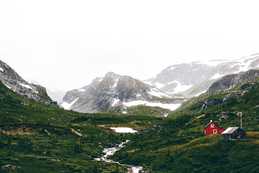 flam en Norvège : ruisseau passant au milieu du bas de montagnes avec des maisons colorés à côté.