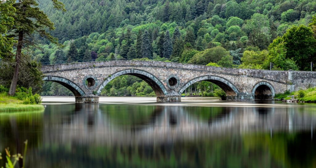 pont au dessus d'un fleuve en écosse entouré d'arbres