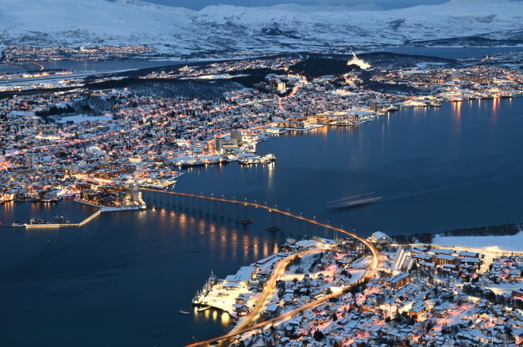 Ville de Tromsø en Norvège de nuit, illuminée par les lumières de la ville. Pont et mer